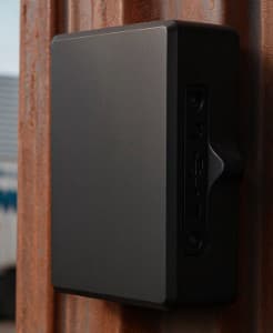 A black rectangular tracker mounted on a container wall.